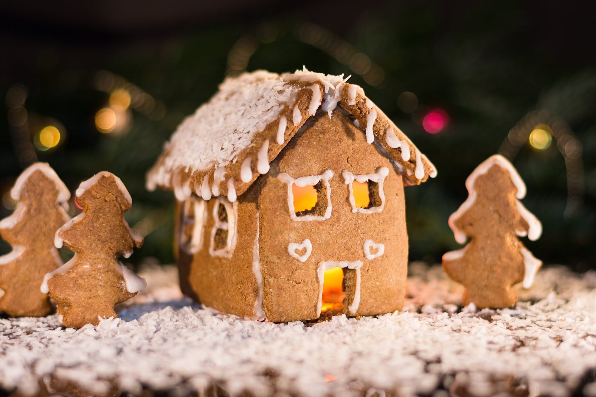 A gingerbread house surrounded by gingerbread trees and coconut snowflakes.