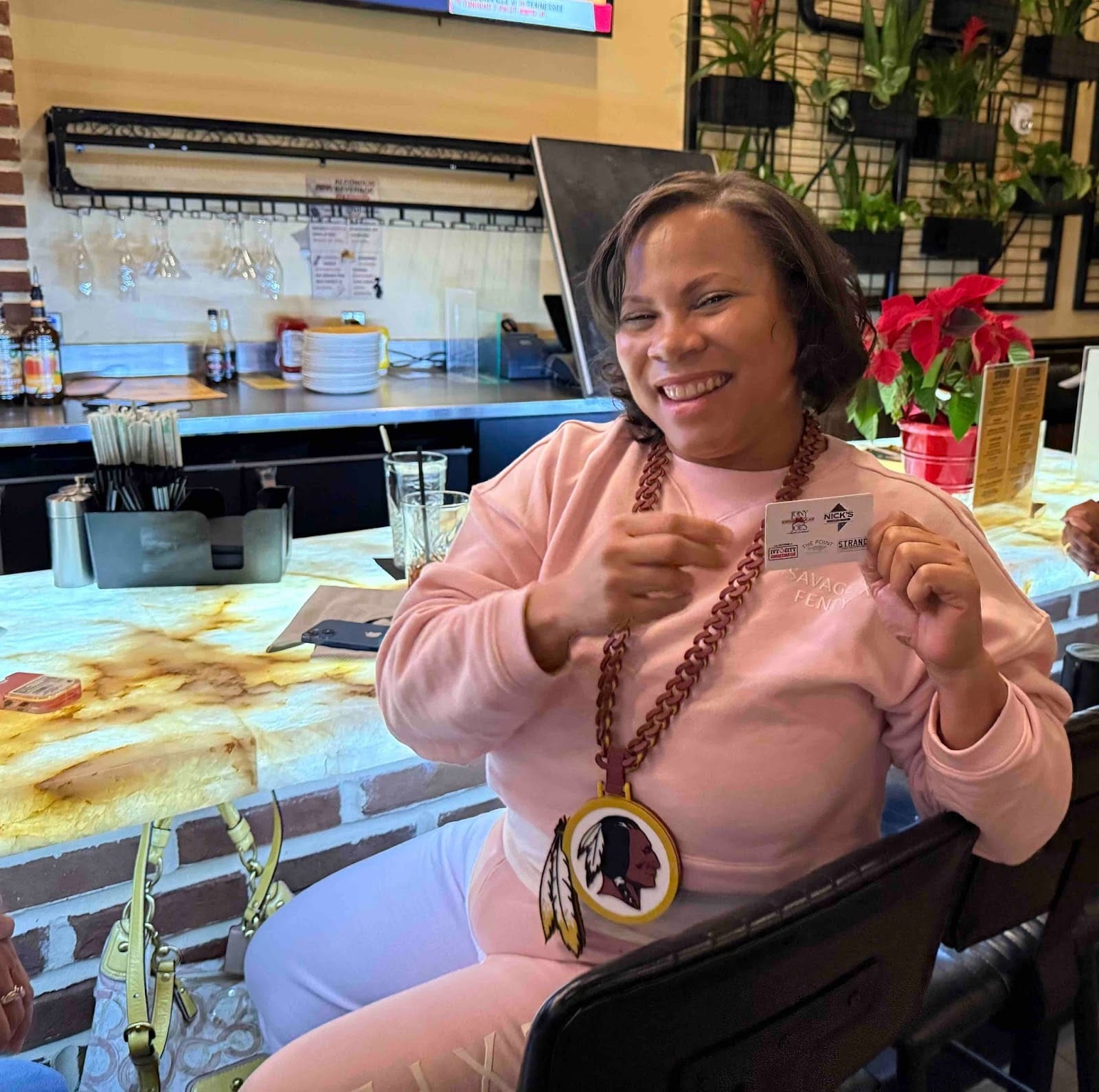A person sits at a restaurant counter showing off a card they won.