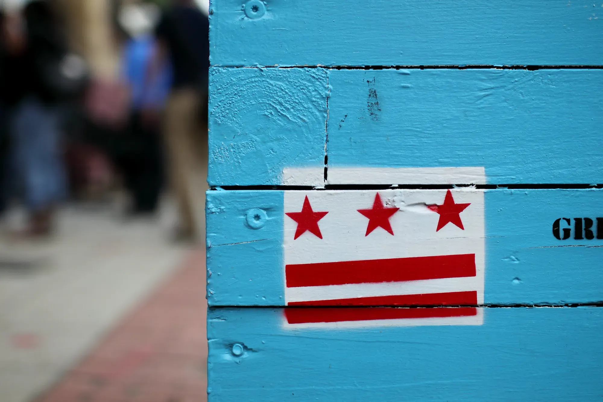 A D.C. flag spray painted onto a wooden structure painted blue.