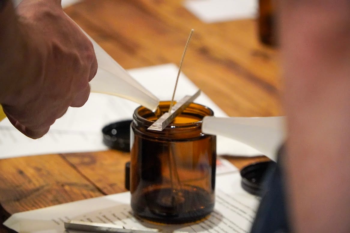 A person pours wax into a jar to make a candle.