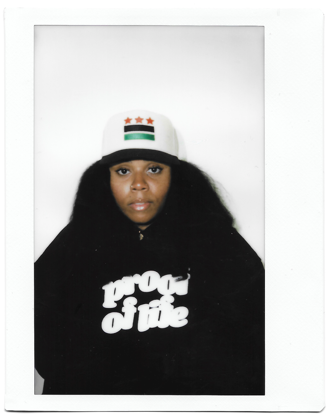 A portrait of Commodity (of Commodity Goods) wearing a shirt that reads "Proof of Life."