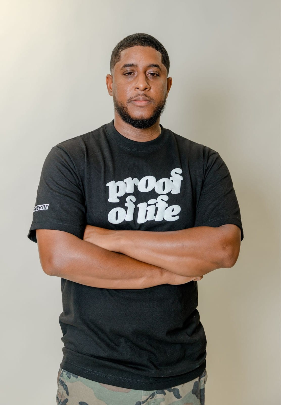 A portrait of Brandon Starkes wearing a shirt that reads "Proof of Life"