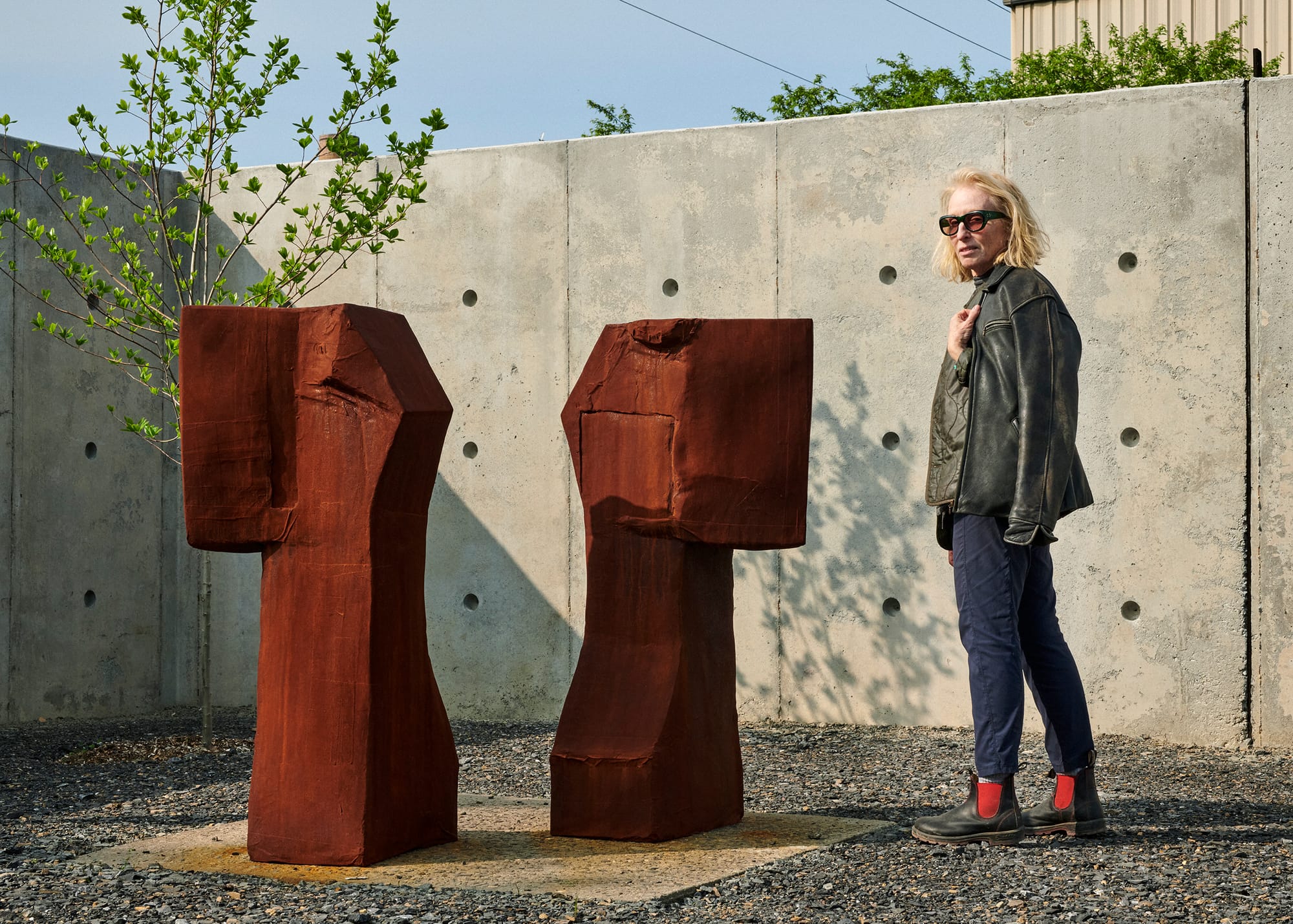 A person stands next to a sculpture in a Brutalist outdoor space
