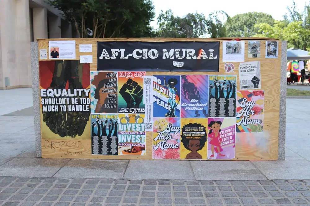 A collection of wheatpaste posters under a sign that reads "AFL-CIO MURAL"
