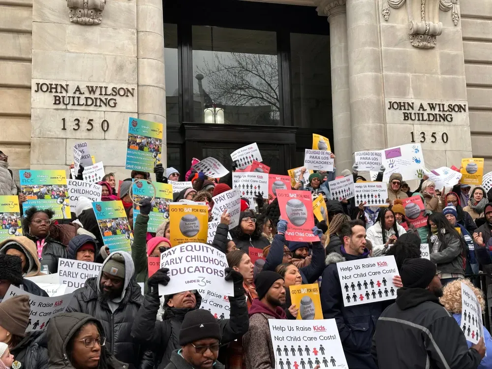 Protestors hold up signs reading "Pay Equity for Early Childhood Educators" outside the John A. Wilson Building in D.C.