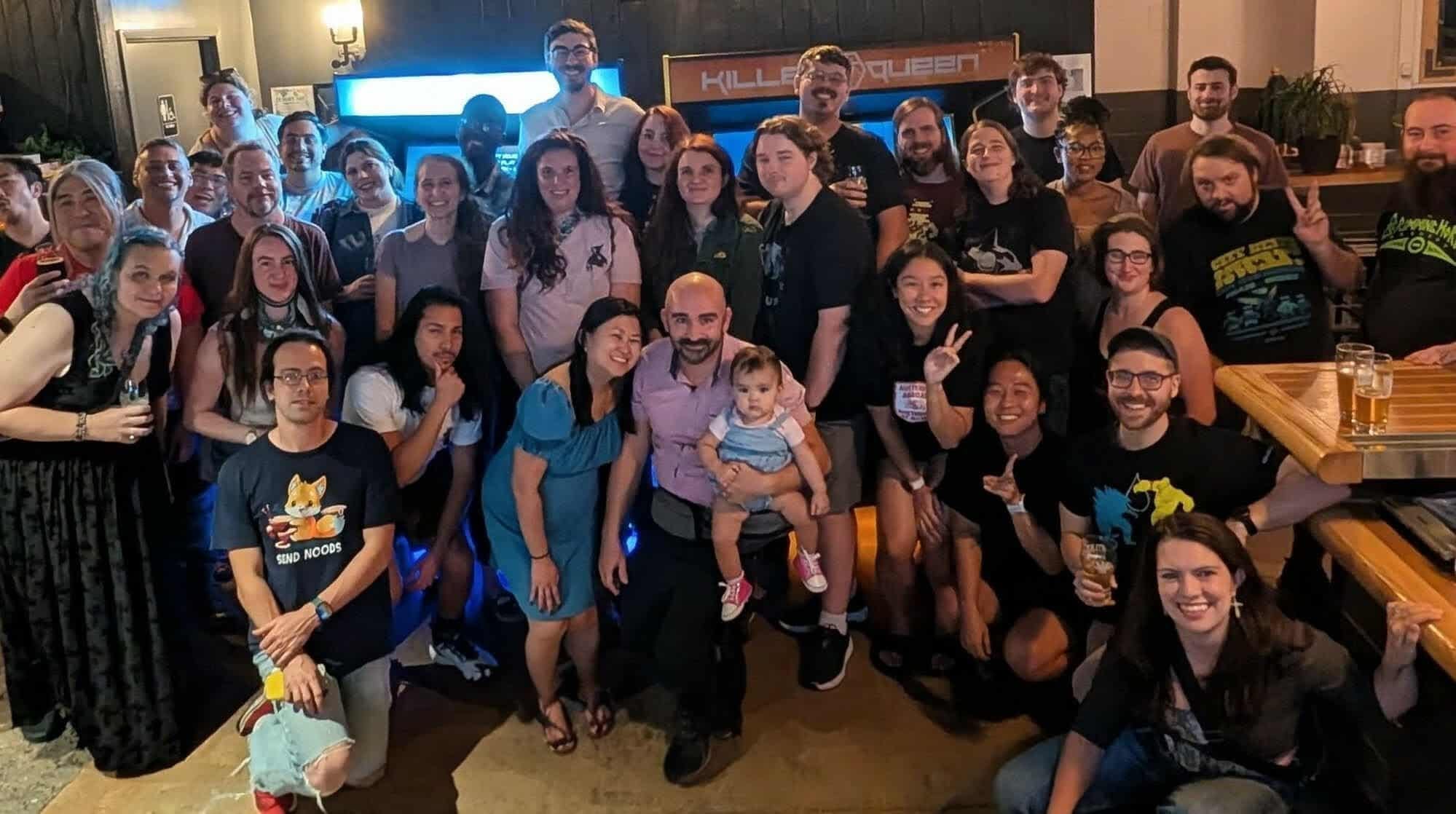 A group of friends posing in front of two Killer Queen arcade games.