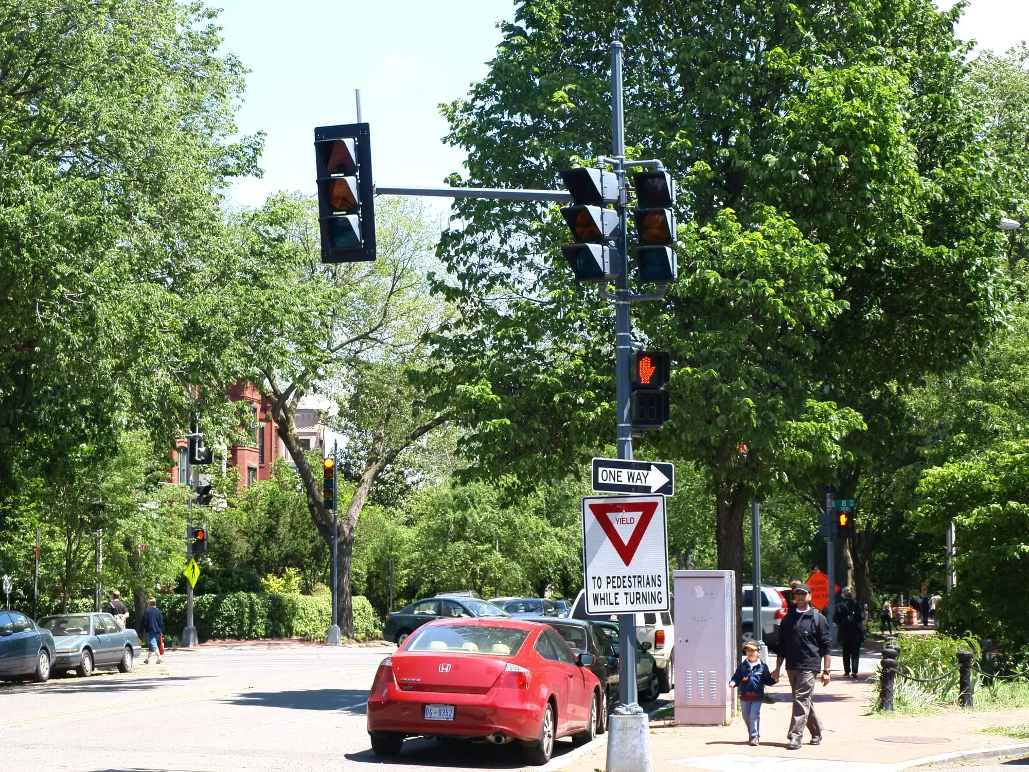An image of a traffic light with pedestrians in the background and signs to yield to pedestrians
