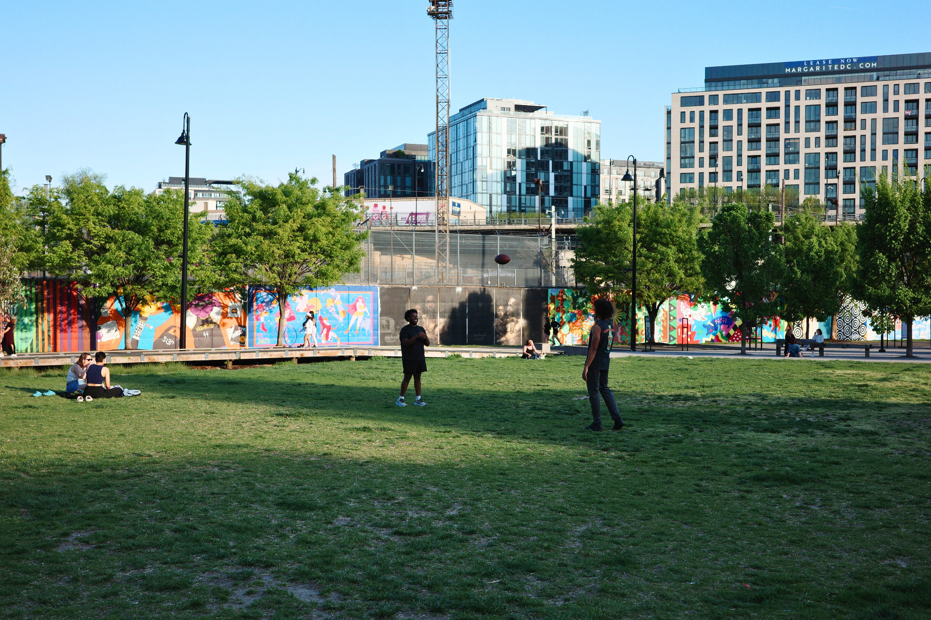 People throw a football and sit out in D.C.'s Alethia Tanner Park.