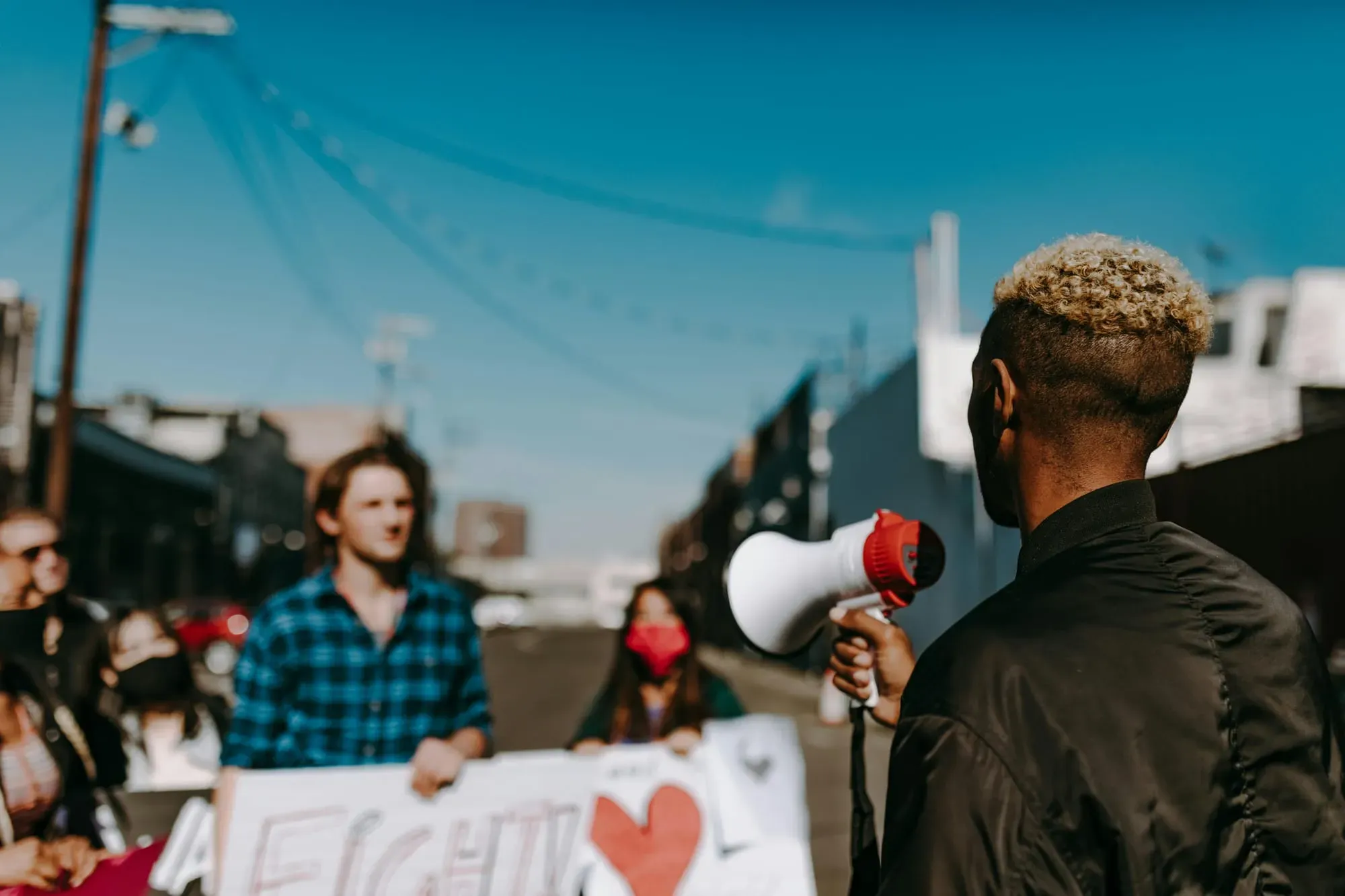 Person holding a megaphone in front of a small group of people outside.