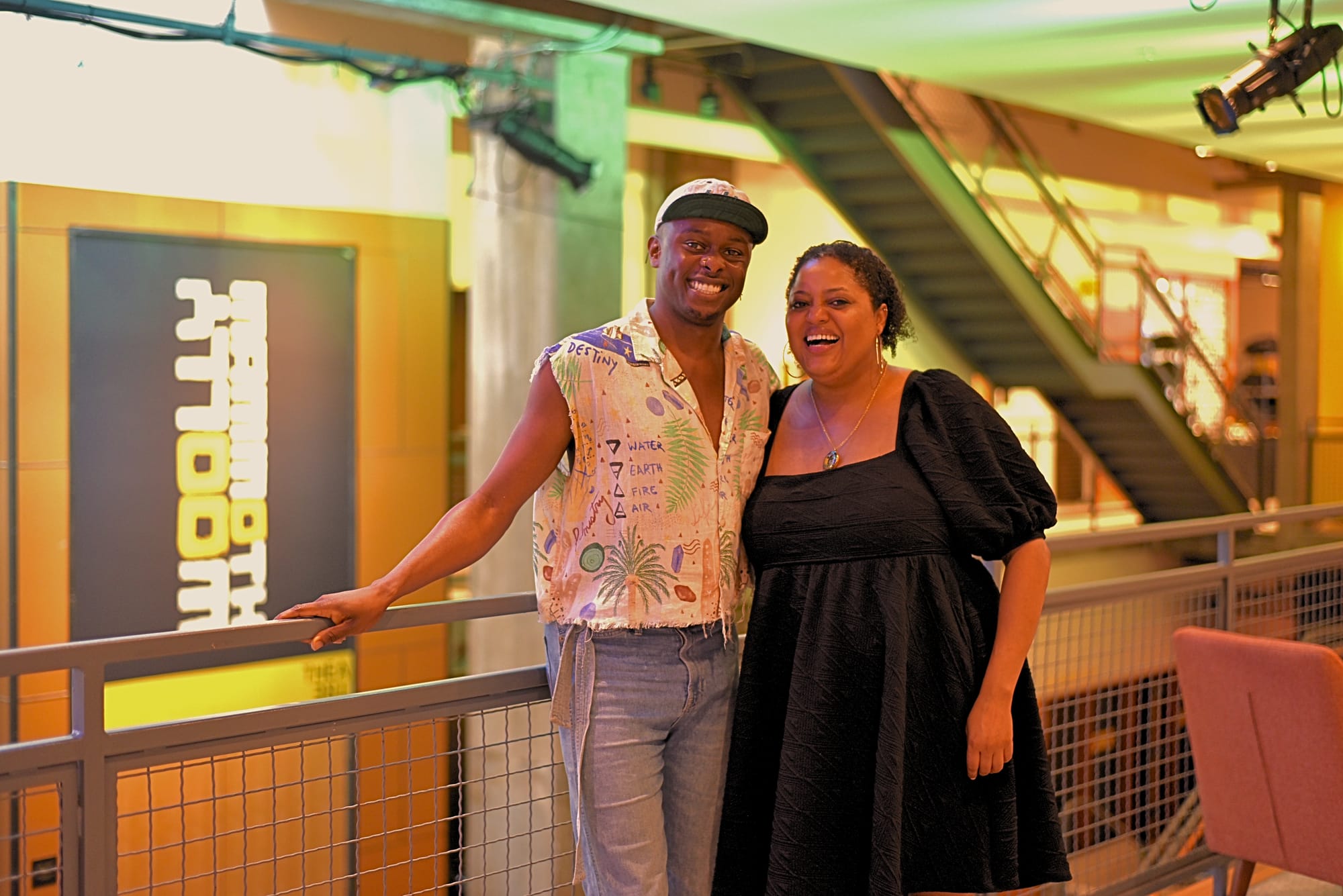 Justin Weaks and Kristen Jackson stand against a railing inside of Woolly Mammoth Theatre.