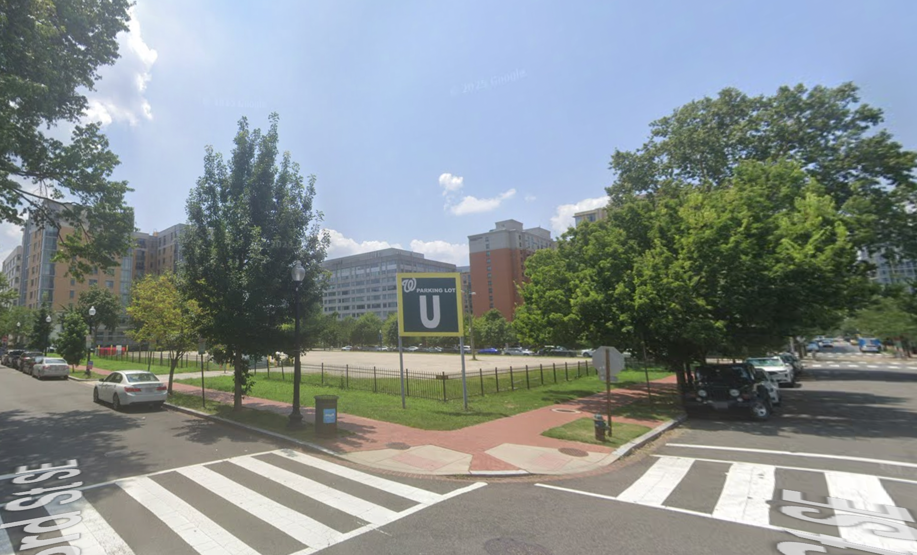 Color photo showing a parking lot next to high-rise buildings. There is a sign that says "Parking Lot U" and includes the Washington Nationals logo.