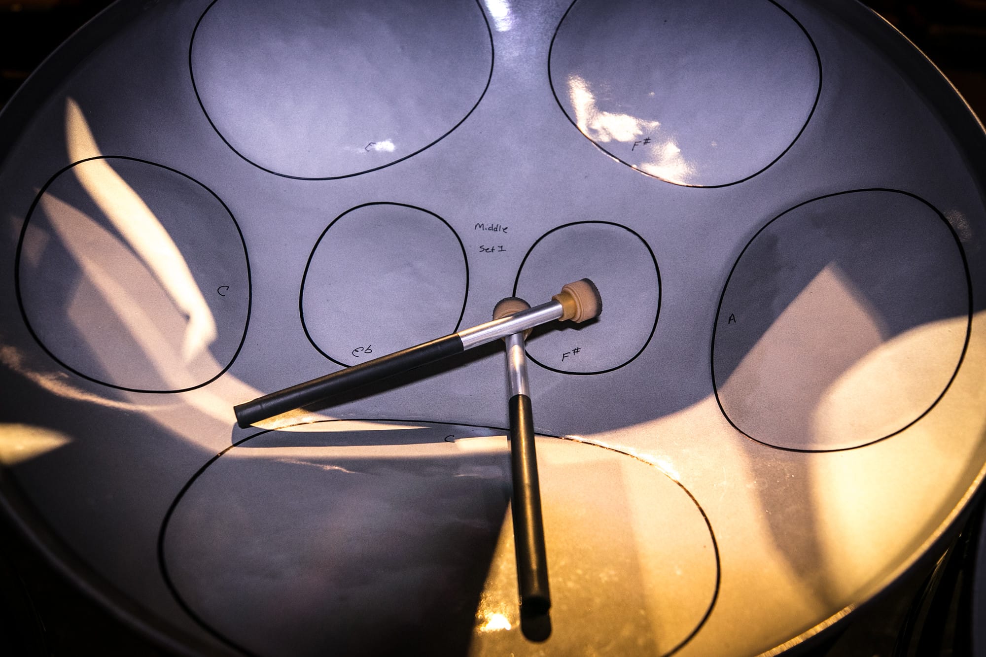 A closeup photo of a steelpan drum with drumsticks.