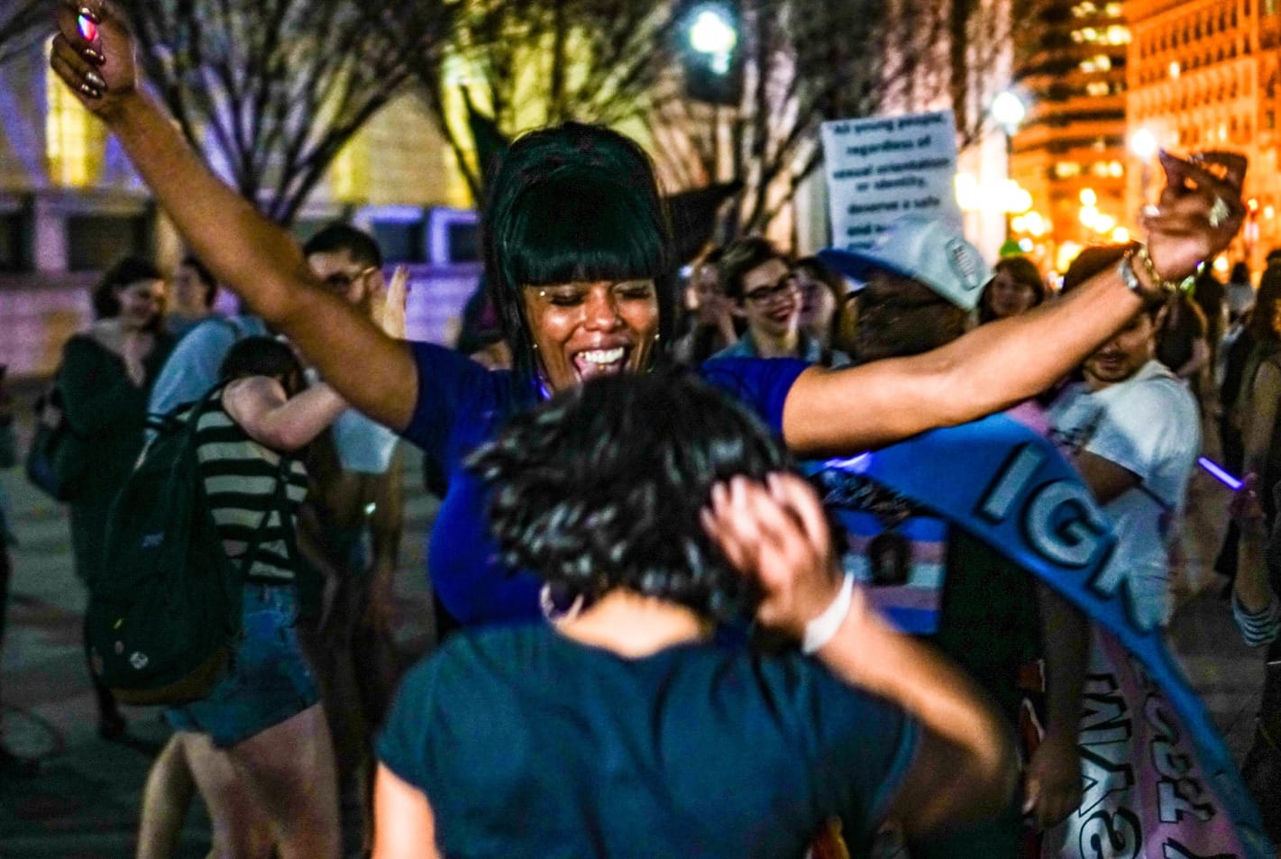 People hug outside a party.