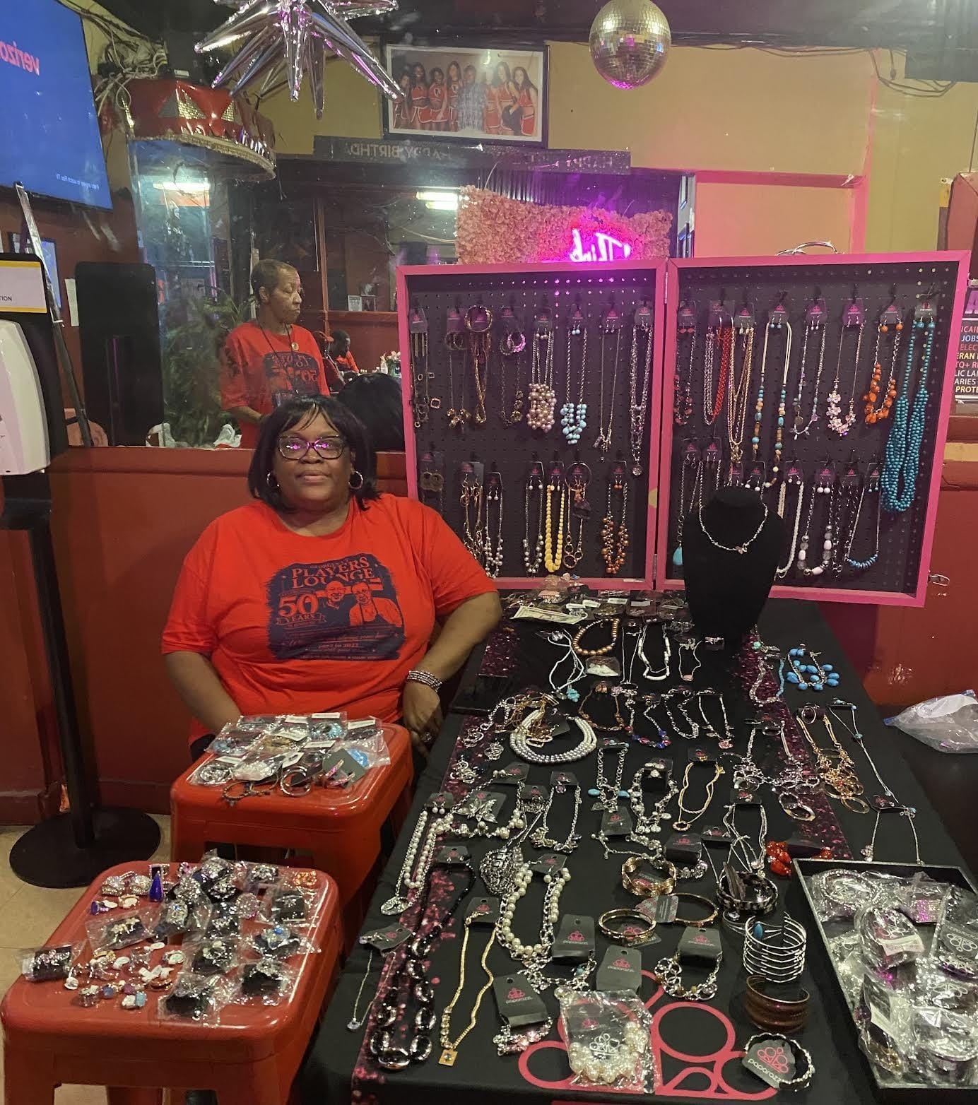 Tanya Brown sites with her jewelry displayed in a Players Lounge booth.