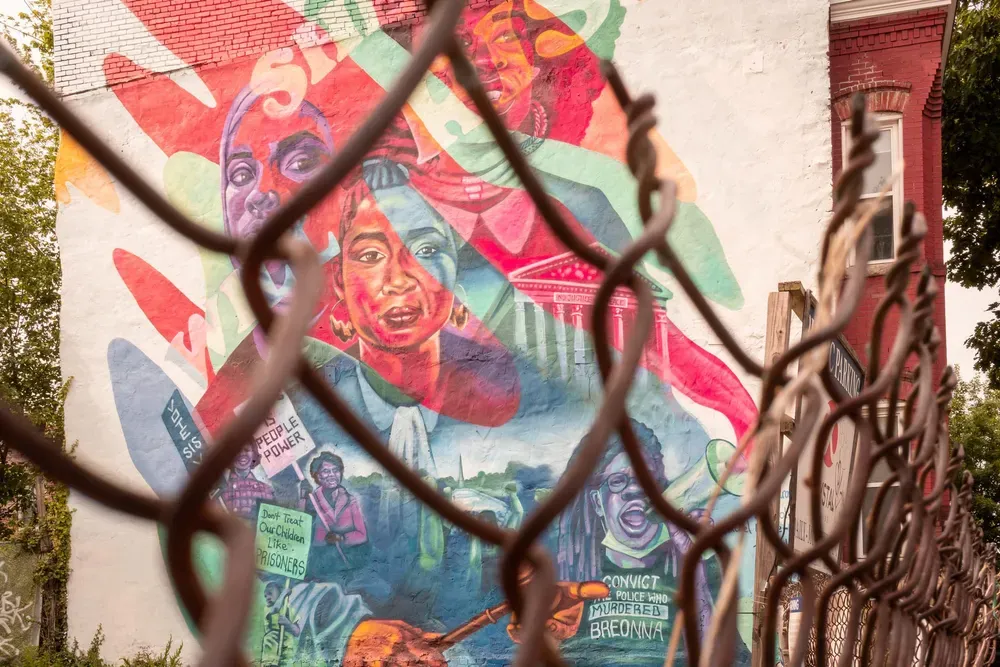 A photo of a mural from behind a fence.
