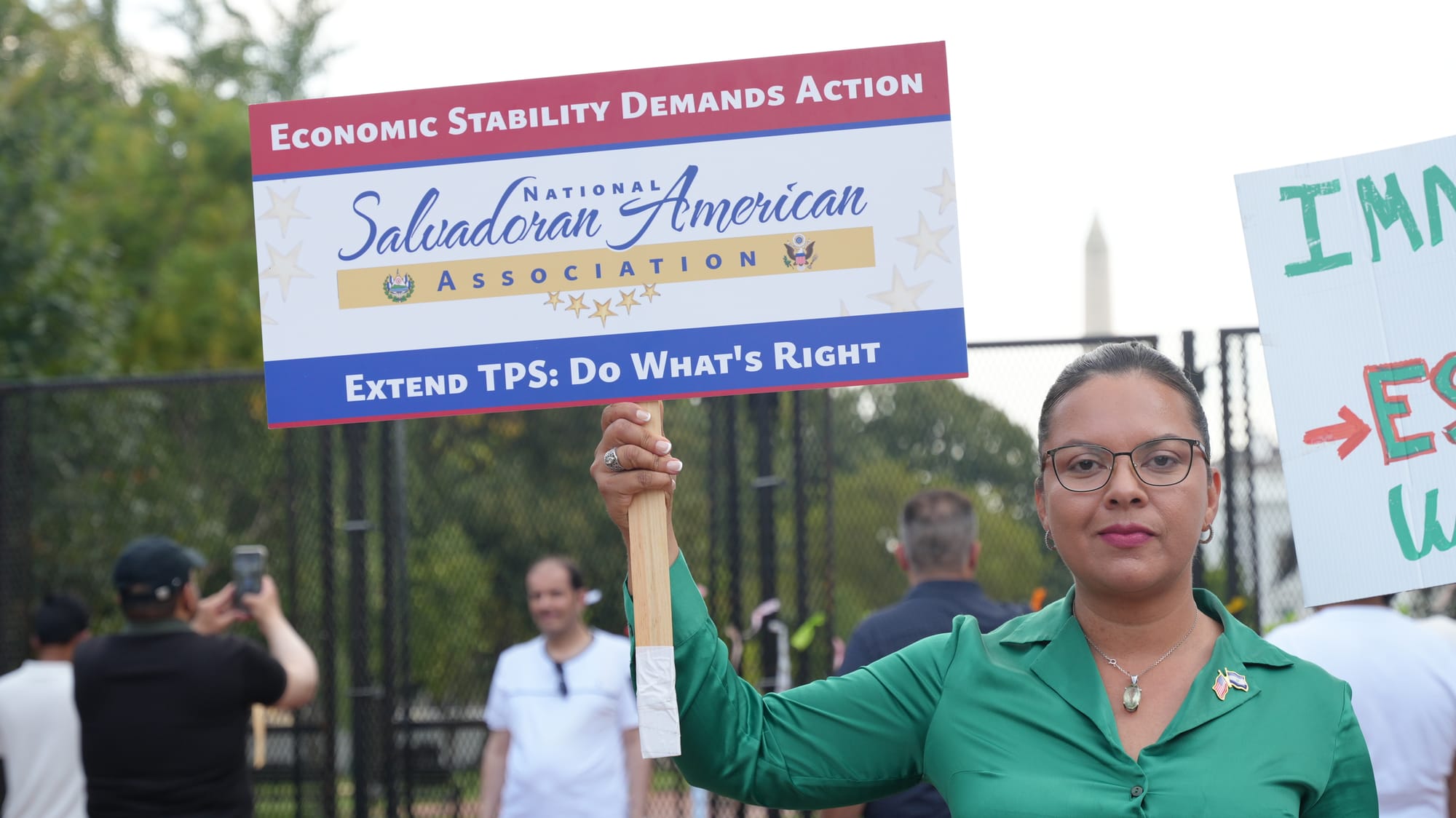 A person wearing green holds a sign that says "extend TPS: Do what's right"