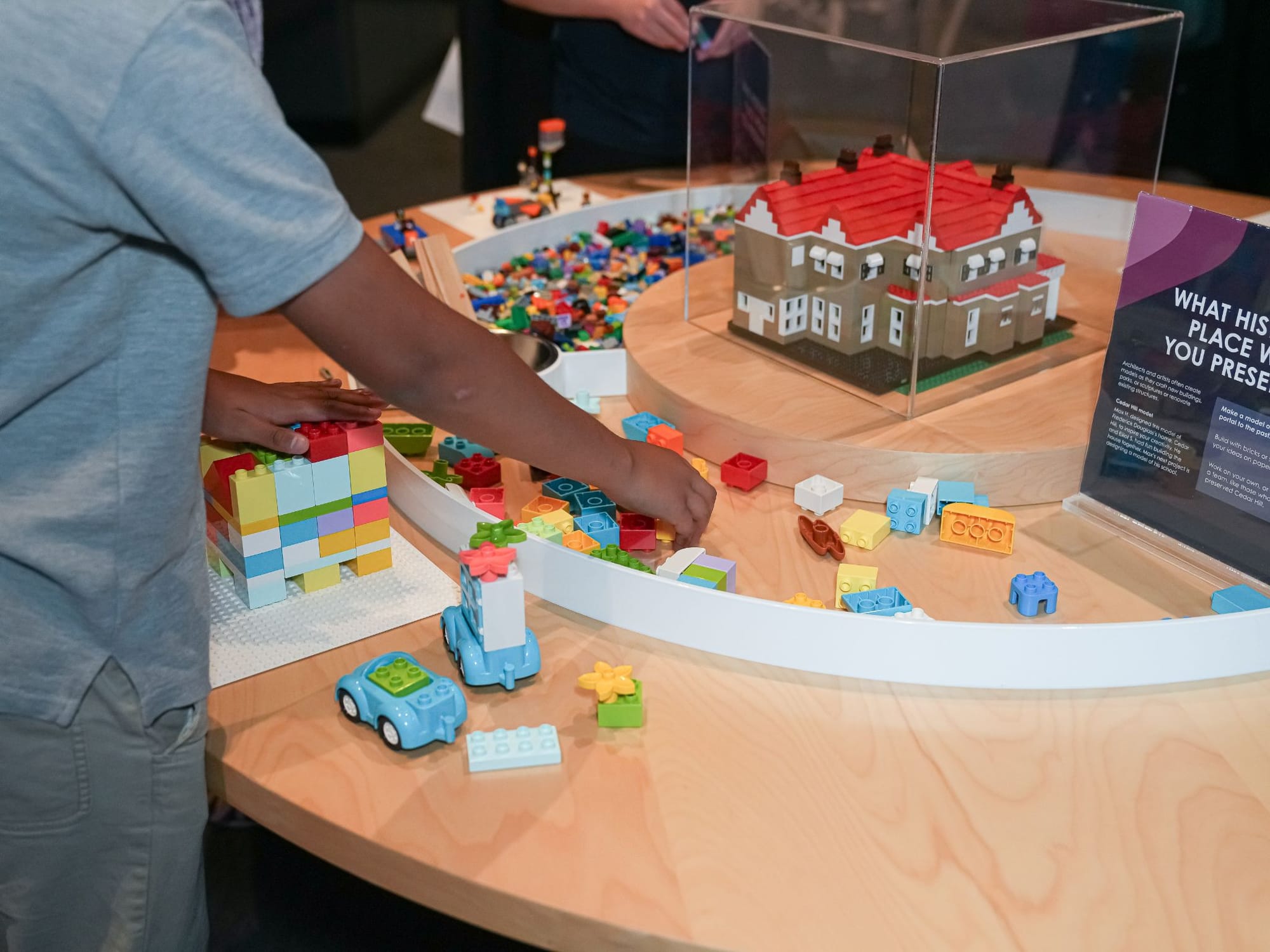 A young person plays with Duplo-style blocks at the American Community Museum.