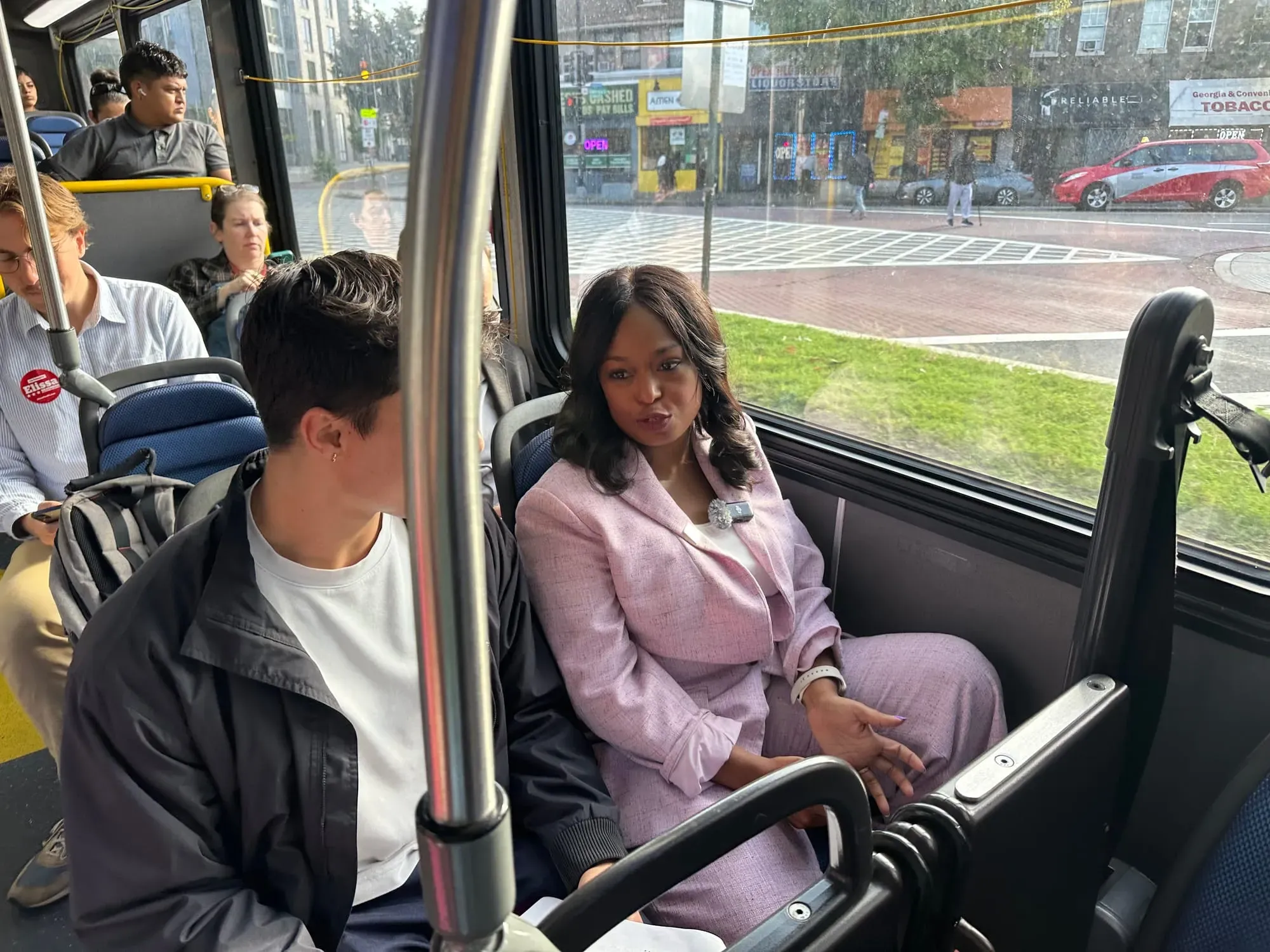 Janeese Lewis George speaks with riders on a bus.