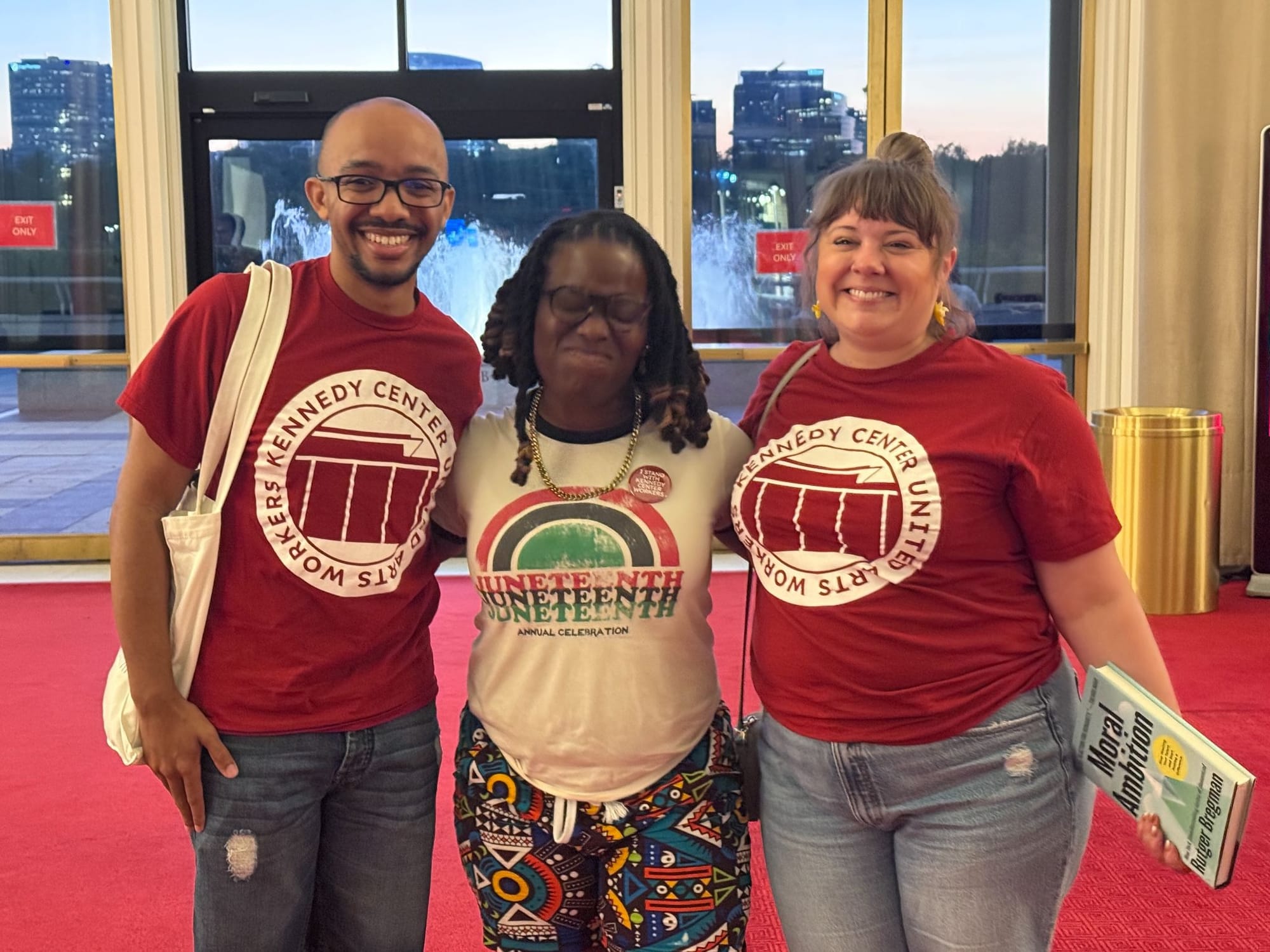 Yasmin Williams, wearing a Juneteenth shirt, stands between two organizers wearing red United Arts Workers shirts at the Kennedy Center.