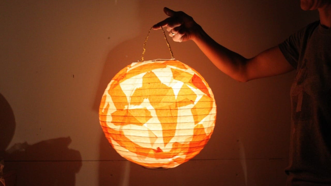 Arm holding a glowing orange lantern. 