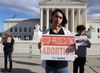 Tres manifestantes sostienen pancartas contra la criminalización del aborto frente a la Corte Suprema de los EE.UU.