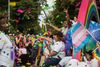 People celebrate and take photos at a queer parade. Colorful confetti is in the air. 