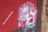 Trumps face spray painted in white on a red wall with #LOCKER ROOM POTUS next to it.