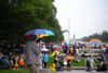People stand on the National Mall near the Lincoln Memorial with umbrellas and rain gear. 