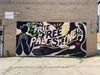 A black mural on a brick wall that reads "Be Free, Free Palestine" in various colors. 