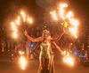 Two dancers hold spokes with flames on the end with a large crowd behind them at the Dupont Circle Fountain. 