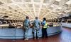 Two National Guardsmen and a Metro worker stand on a balcony overlooking the tracks at a Metro station.