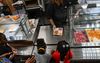 A school lunch worker passes a plate of food to childre standing in line at a school cafeteria
