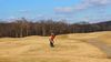 Person in a red shirt gets ready to hit golf ball on open course
