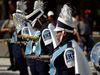 Members of a high school marching band wearing blue and white uniforms and holding saxophones