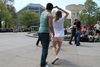 A couple dancing in a park; the man is twirling the woman. 