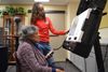 A person demonstrates to another person how to use a voting machine