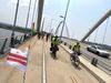 Bikers ride across the Frederick Douglass Memorial Bridge with a D.C. flag in the foreground