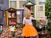 A picture of a kid in an orange tutu opening a little free library full of puzzles.