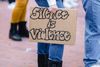 A cardboard sign reads "silence is violence."