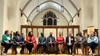 The the candidates for an At-Large seat on the D.C. Council are all seated in chairs in a church.