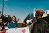 Man holding a megaphone in front of a small group of people outside.