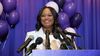 A photo of Janeese Lewis George at a press conference with a purple background.