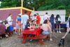 People sit on a red picnic table at an outdoor Fourth of July celebration.