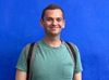 A picture of a person in a green shirt with a blue background.