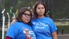 Two people wearing blue shirts with their arms around each other.