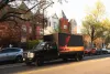 A truck with video art on the side drives along a D.C. street featuring rowhouses.