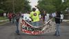 A group of tenants march down the street with a sign that reads "Stop Subsidizing Slumlords."