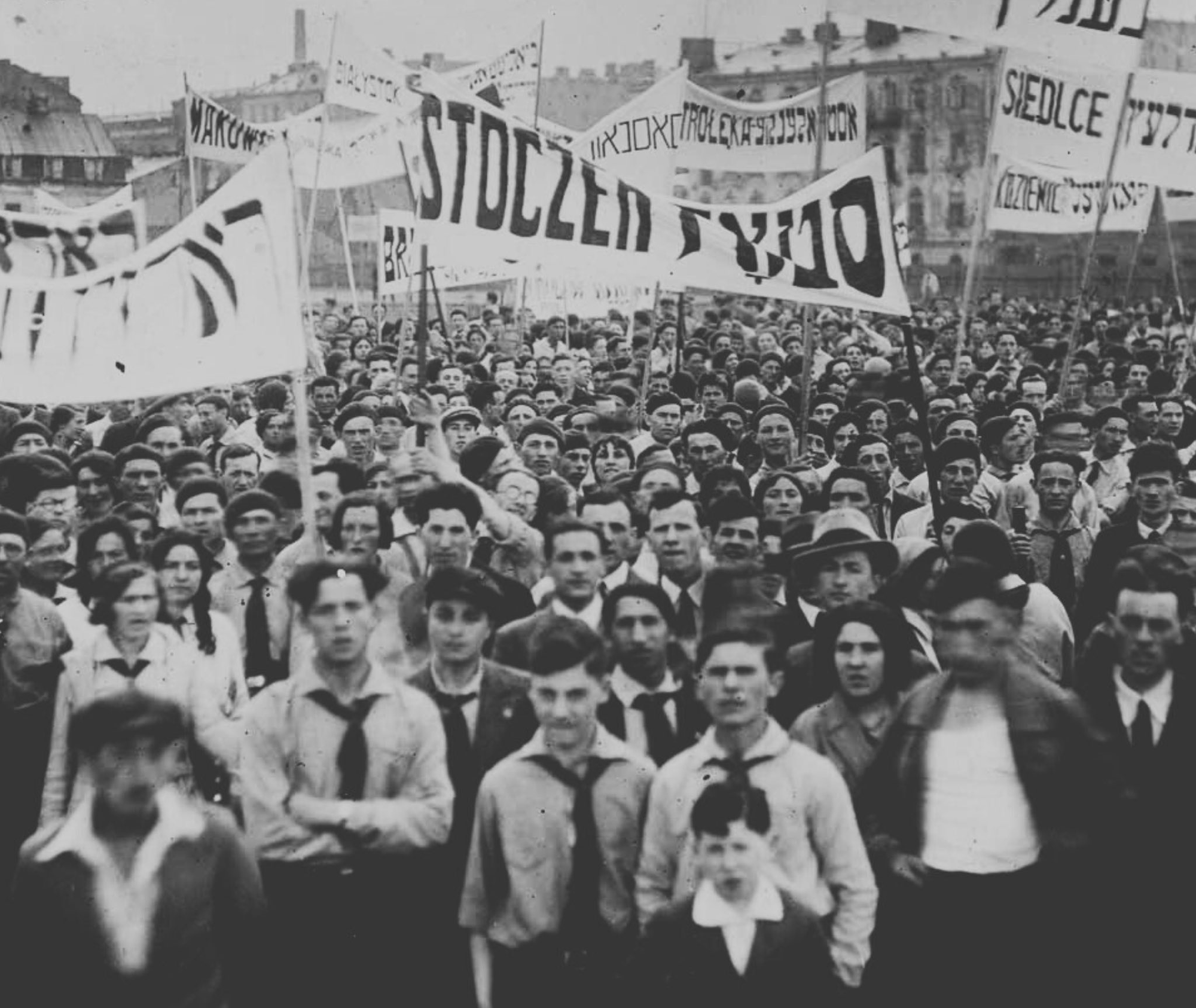 A large group of youths carrying banners with text in Yiddish & Polish, facing the camera