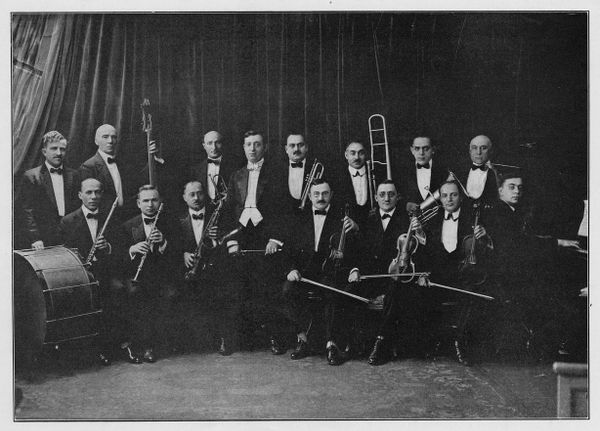 A black and white photo of 15 men in tuxedos holding various instruments and looking at the camera