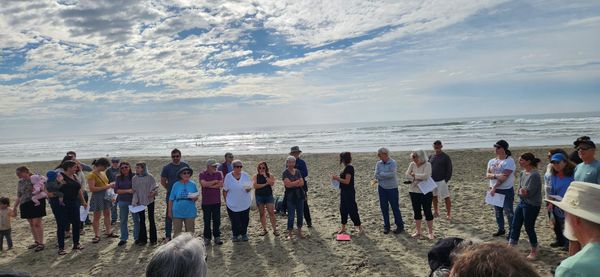 several dozen Jews standing on the beach during a Tashlich service in San Franci